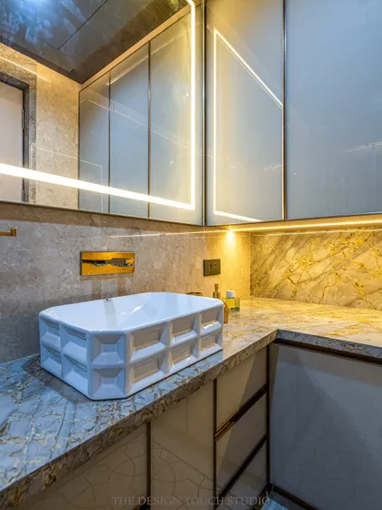 A close-up of the designer washbasin and the warm, ambient lighting from the backlit mirror and under-cabinet LEDs. These details create a luxurious and inviting atmosphere.
