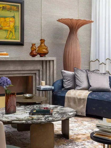 A detailed shot of a seating nook, showcasing a curved sofa, a stone fireplace, and carefully selected art. This corner exemplifies how we layer textures and colors to create depth and interest.