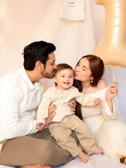 Parents kiss their smiling son's cheeks in a loving family portrait from his first birthday session. This image is a beautiful expression of family love and celebration.