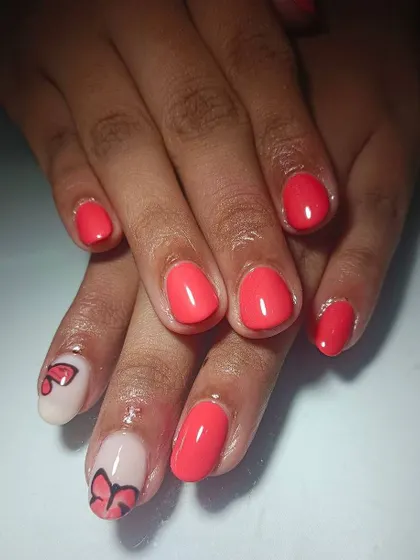 A sweet and simple design with bright coral polish and a hand-painted butterfly accent nail on a negative space background.