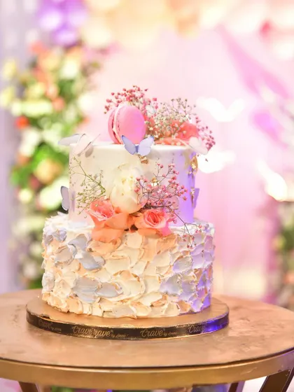 I also partner with talented home bakers to provide delicious and beautiful theme-based cakes. This two-tier cake is decorated with fresh flowers, macarons, and delicate butterflies.