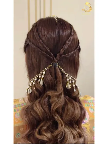 A perfect Haldi hairstyle with soft waves and criss-cross braids. The look is completed with a beautiful hair accessory featuring pearls and shells.