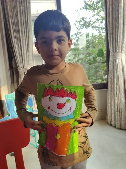 This young boy proudly displays his colorful clown artwork. Our classes guide students to create complete characters, helping them build confidence with every successful project.