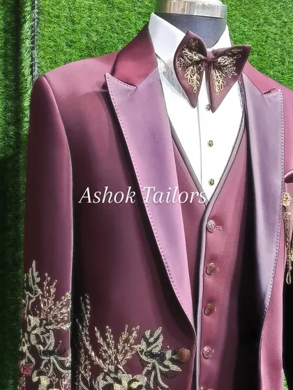 A close-up of our maroon velvet suit with beautiful gold embroidery on the sleeve and a matching embellished bow tie. The fabric and work are pure luxury.