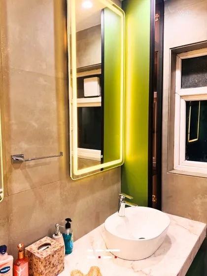 A close-up of the double vanity, showing the sleek chrome faucets, vessel sinks, and the warm glow from the backlit mirrors against a modern concrete-finish wall.