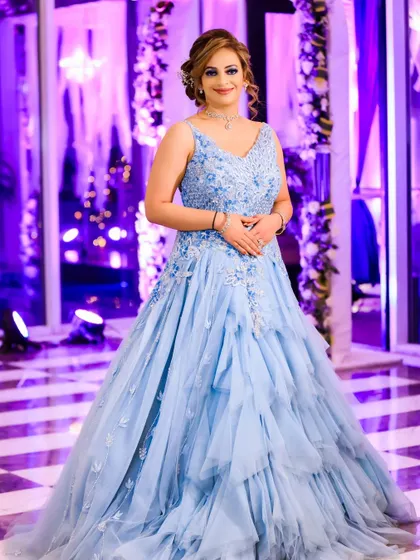 A full-length portrait of the bride in her stunning light blue gown. The purple-lit background and elegant decor create a modern and chic atmosphere for her engagement.