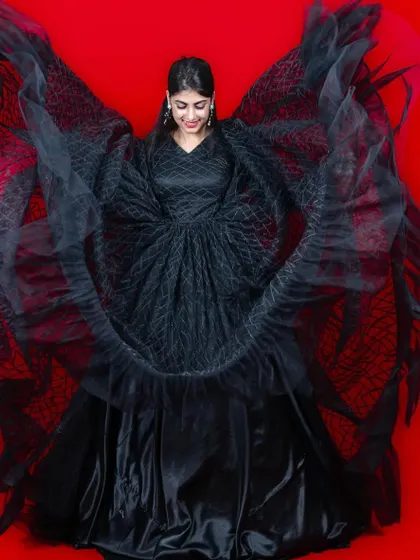 This black gown with wing-like sleeves is a dramatic and high-fashion choice for a unique photoshoot.