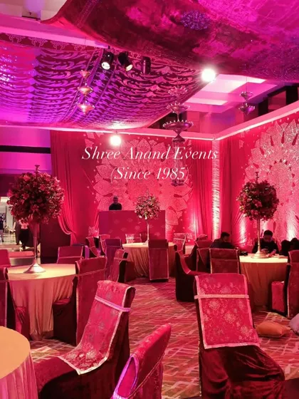 An immersive event space bathed in magenta light, with elegantly set tables and a DJ booth, ready for a night of celebration.