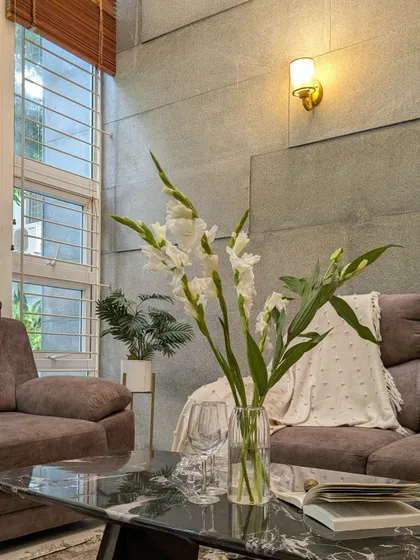 A close-up on the styling details, where a black marble coffee table and fresh flowers add a touch of elegance and life to the room.