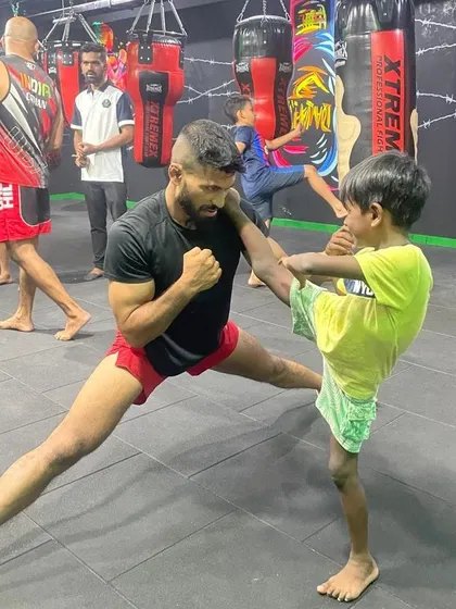 Correcting a young student's kicking form during a training session. Proper technique is crucial for both power and injury prevention.