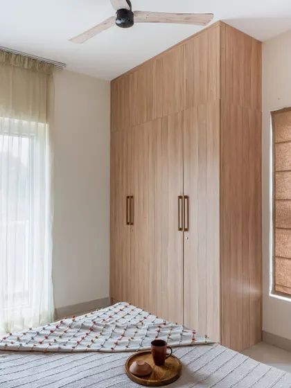 A simple yet elegant floor-to-ceiling wardrobe in light wood laminate, providing ample storage in a guest bedroom.