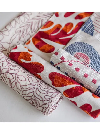 This fabric collection from 'Vaya' offers a whole range of textiles in a plethora of textures and patterns. This swatch shows a mix of embroidered and printed fabrics, perfect for a bohemian-chic aesthetic.