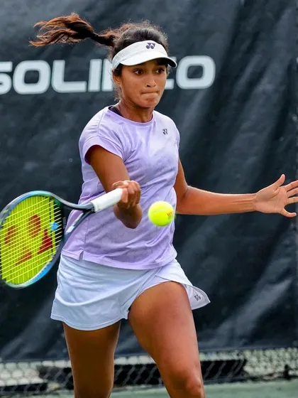 A dynamic shot of Sahaja hitting a forehand on the run, highlighting her agility and court coverage during a high-level ITF match.