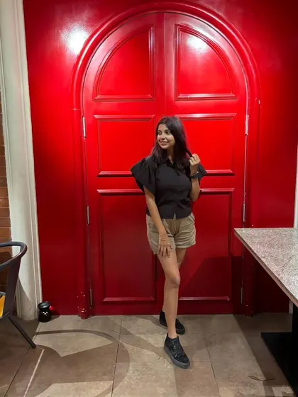 Posing against a bold red door. The simplicity of my black and khaki outfit makes the background pop.