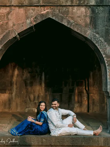 A relaxed moment of connection. This image of Ankush and Aishwarya sitting back-to-back captures their easy comfort with each other against a dramatic architectural backdrop.