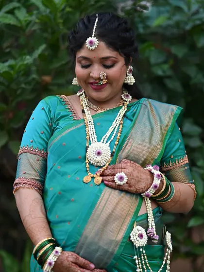 A heartwarming shot of the mom-to-be cradling her baby bump. The entire look, from the saree to the floral jewelry, is designed to celebrate motherhood.