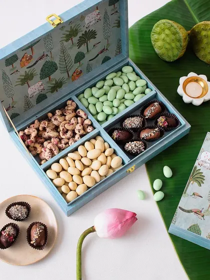 This festive hamper is a treat for the senses, featuring Rose Cashews, Elaichi Badam, Pista Badam, and Chocolate Coated Dates.