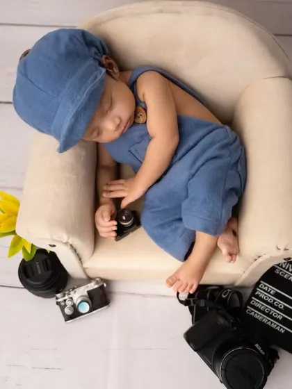 Another angle of the director-themed newborn shoot, capturing the baby curled up on the miniature couch with all the fun props around him.