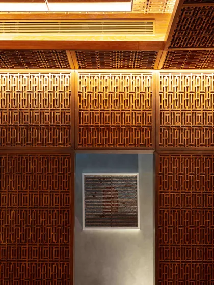 A detail of the Pinjirakari-inspired lattice work, which masterfully camouflages the kitchen door. This technique, rooted in Mughal and Kashmiri woodwork, is used here to create a seamless and immersive environment.
