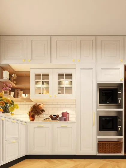 A timeless white kitchen with classic cabinetry and gold hardware. The design includes an integrated appliance tower for the microwave and oven, as well as a glass-front pantry for display and storage.