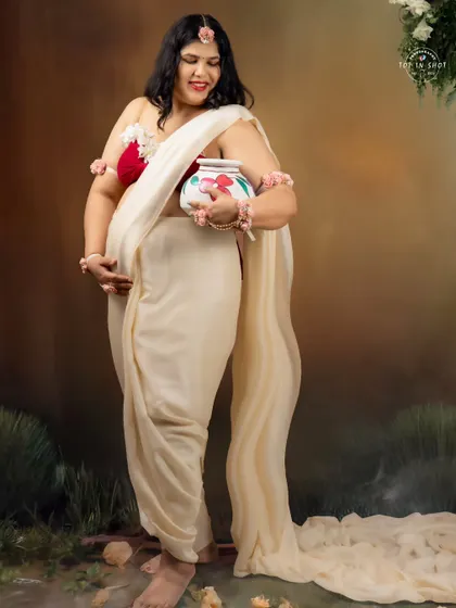 A beautiful re-imagining of Shaakunthalam, with the mom-to-be in a white saree adorned with flowers, holding a painted pot.