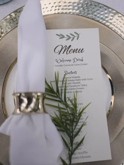 An elegant table setting with a hammered metal charger plate, crisp white napkin, and a personalized menu card.