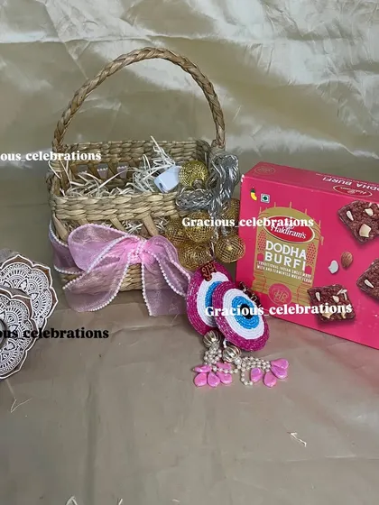 Celebrate Diwali with this festive basket filled with traditional treats. It includes a box of Dodha Burfi, decorative evil eye hangings, and fairy lights to add sparkle to the celebration.