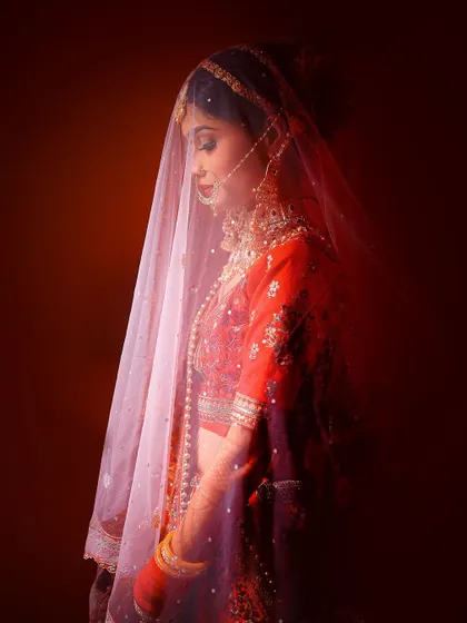 A moody and artistic portrait of a bride under her veil, using red light to create a dramatic effect.