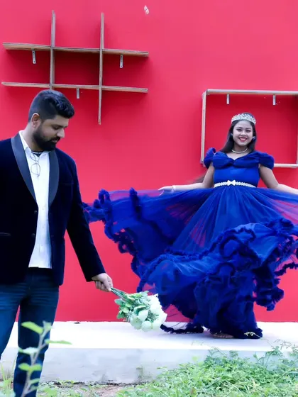 A whimsical maternity photo with the father-to-be offering flowers to his partner, who is wearing a royal blue ruffled gown.