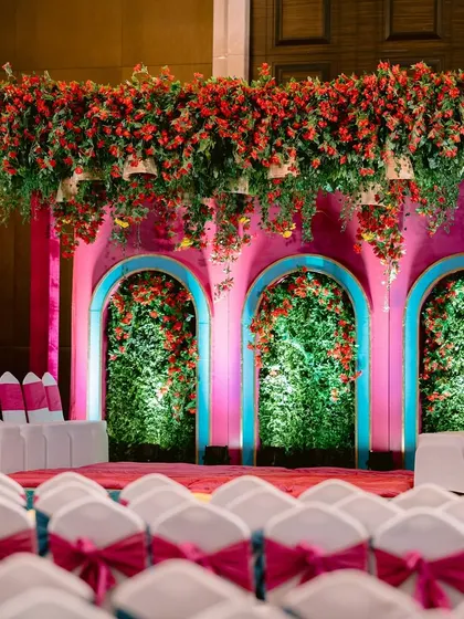 The stage setup for the Mamera ceremony, featuring a stunning floral canopy and a backdrop of pink and blue arches.