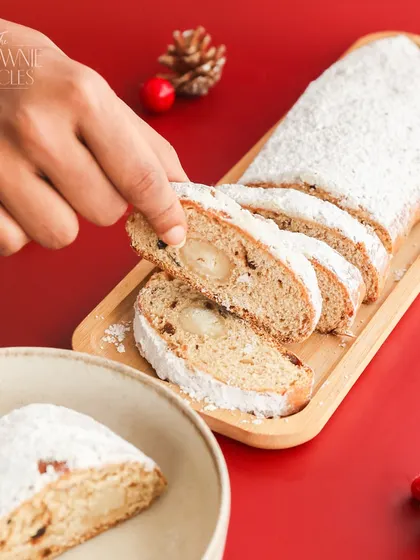 Slicing into our festive Stollen Bread. You can see the rich marzipan filling and the assortment of fruits and nuts that make this holiday loaf so special.
