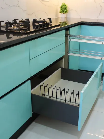 This image displays two key storage solutions: a large drawer with a plate and thali rack, and a multi-level pull-out rack for bottles and jars, demonstrating our focus on efficient kitchen organization.
