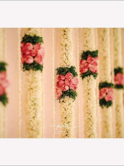 The decor for this wedding ritual features tuberose, lotus blooms, and suspended bells. The urli filled with vibrant flowers completes the serene and magical atmosphere.