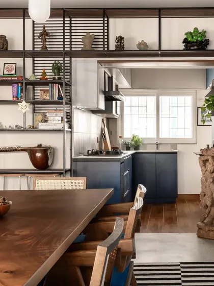 The dining room is the heart of the Keepsake home, featuring a large 8-seater table that encourages gathering. It is surrounded by open shelves displaying the client's artifacts, blending life, travel, and design into a single, cohesive narrative.