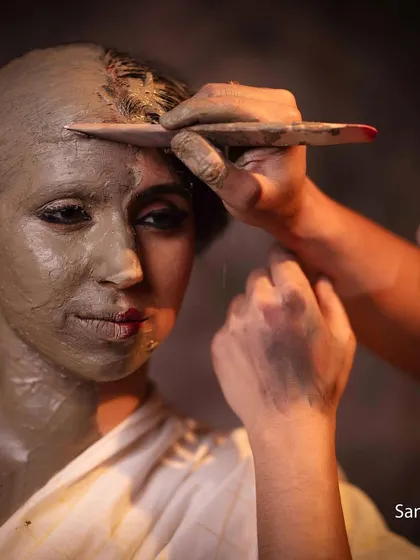 The artist's hand sculpting the clay, a direct visual metaphor for how identity is shaped by external forces.