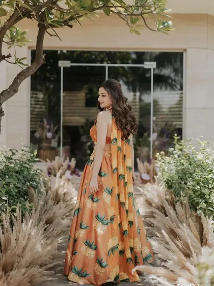 The back view of the client's half-up style, showing off her long, wavy hair against her beautiful floral lehenga.