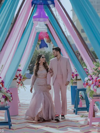 The couple makes a stylish entrance through an aisle of pastel-colored drapes.