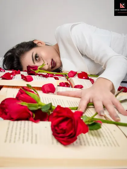A dramatic overhead shot from the 'Bittersweet Memories' series. The model lies among the scattered rose petals and books, creating a visually compelling narrative of love and loss.