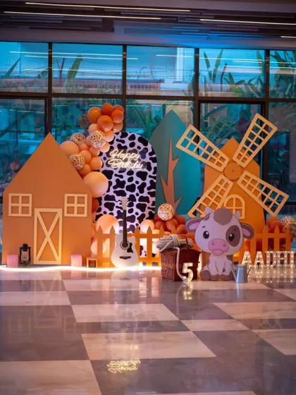A charming cowboy theme party, complete with a barn, a windmill, and a cute cow character. The orange and cow-print color scheme creates a fun and rustic atmosphere perfect for a little buckaroo.