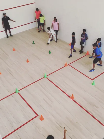 A coach directs players through a multi-directional cone drill. This kind of structured practice is vital for developing the agility needed to cover all four corners of the court effectively.