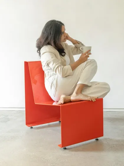 The minimalist chair in use, demonstrating its ergonomic form. The angled backrest provides natural support, making it a comfortable piece of furniture that is versatile enough for offices, public spaces, or homes.