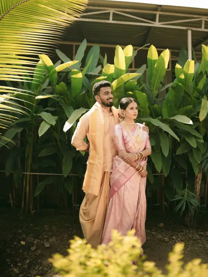 A classic, poised portrait of the couple amidst lush greenery, showcasing their elegant wedding outfits.