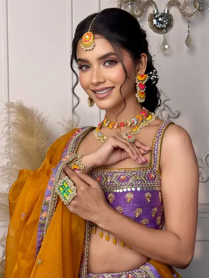 A smiling portrait of the 'Khushnuma' look. The makeup is fresh and joyful, perfectly matching the colourful jewellery and the mood of a mehendi ceremony.