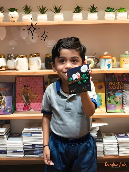 A young boy holds up his clay art piece, proud of the little world he created with his own hands.