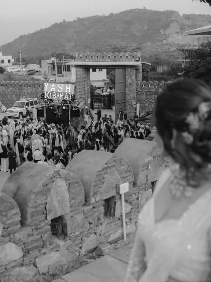 The bride gazes down from the terrace, her heart filled with joy as she watches her baraat arriving in a grand celebration.