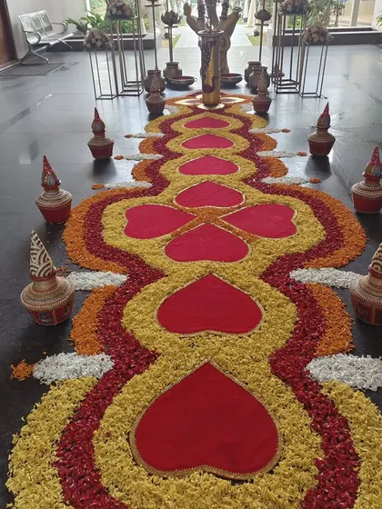 A traditional and colorful welcome rangoli made entirely of flower petals. The heart-shaped patterns and surrounding clay pots create a beautiful and auspicious entrance for any celebration.