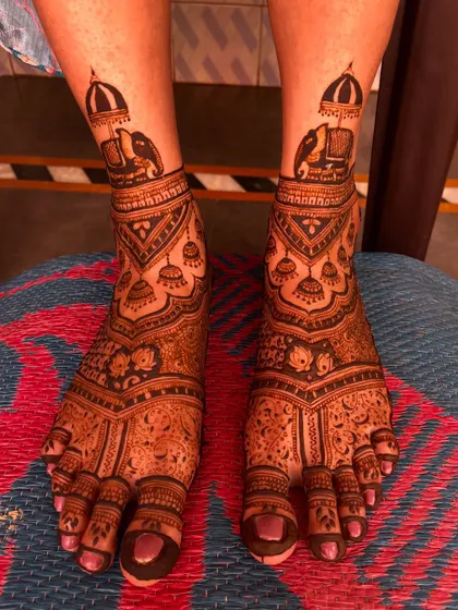 A classic bridal feet design with elephant motifs on the ankles and jhumka (earring) patterns below. The floral details on the toes complete the look.