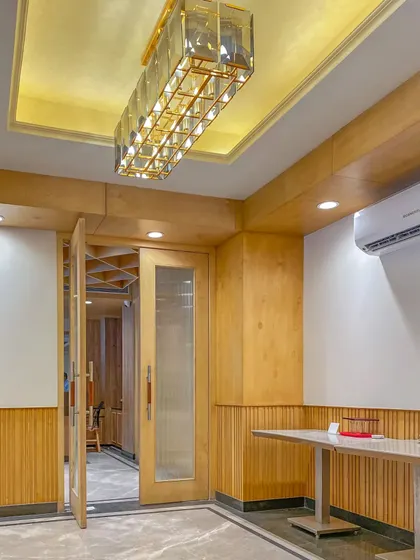 An interior view of the Bhopal project during construction, showing the interplay of wood paneling, recessed lighting, and elegant glass doors that define the space.