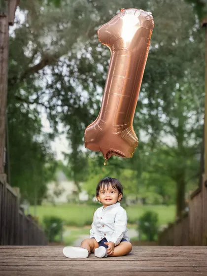 A classic first birthday portrait. The giant number one balloon adds a fun, celebratory touch to this adorable photo of the birthday boy.