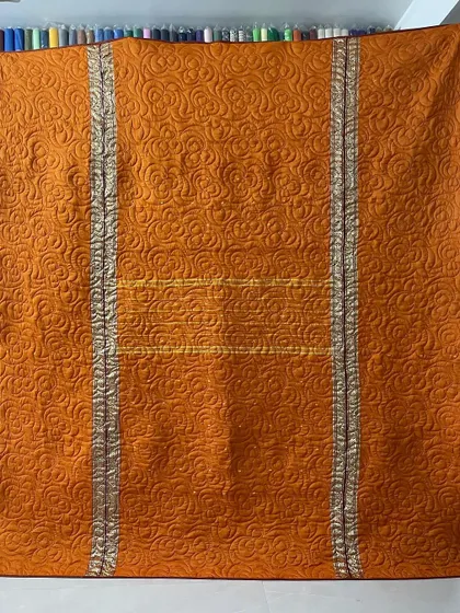 An orange and gold saree transformed into a warm, inviting memory quilt. The silver borders are carefully integrated, and the rose-patterned longarm stitching adds a luxurious feel.